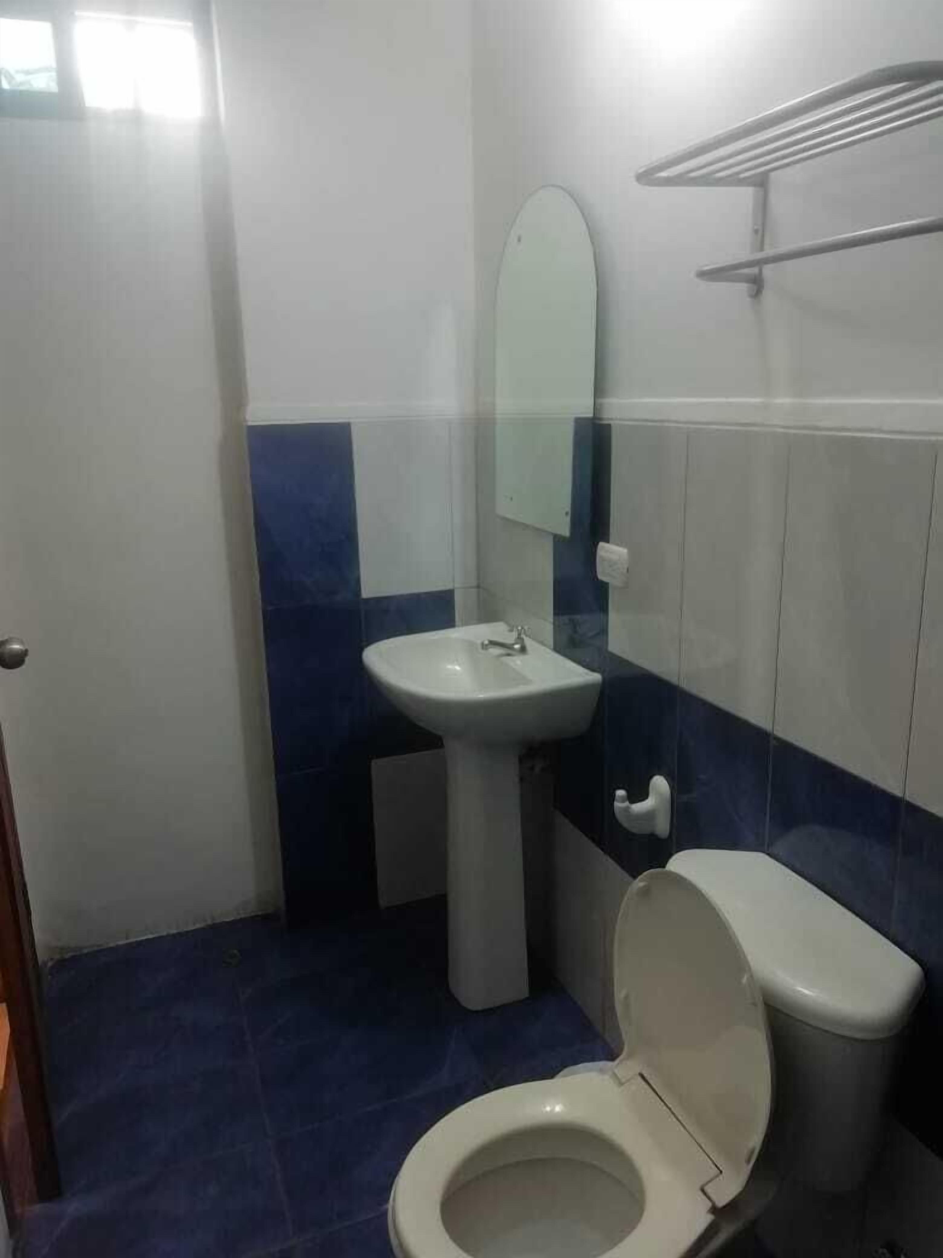 Un baño pequeño con inodoro, lavamanos y espejo.