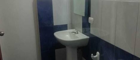 Un baño pequeño con inodoro, lavamanos y espejo.