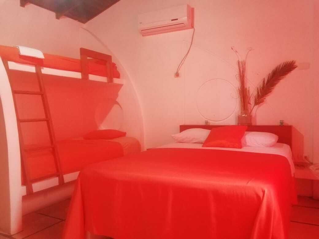 A room with a bunk bed, a single bed, and a bedside table with a lamp.