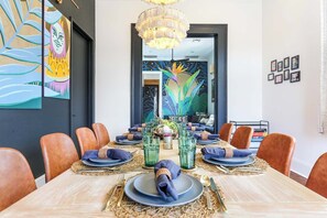 A dining area with a large table set for six, surrounded by leather chairs.