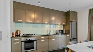Een moderne keuken met roestvrijstalen apparatuur, houten kastjes en een glazen spatwand.