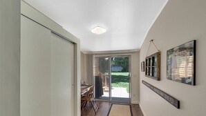 Un pasillo con piso de madera, una puerta corredera de vidrio que da a un patio y un letrero en la pared.