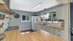Una cocina moderna con encimera de madera, armarios blancos y horno empotrado.
