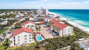 Un hôtel situé sur la côte, composé de plusieurs bâtiments, doté d’une piscine et offrant une vue sur la plage.