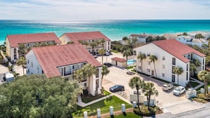 Un quartier résidentiel en bord de mer, avec des bâtiments aux toits recouverts de tuiles rouges, entouré de verdure et offrant une vue dégagée sur l’océan.