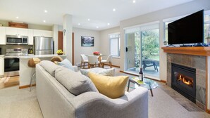 Ein modernes Wohnzimmer mit Sofa, Kamin, Fernseher und Küchenzeile inklusive Kühlschrank und Mikrowelle.