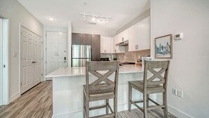 Une cuisine moderne dotée d’un îlot central, d’appareils électroménagers en acier inoxydable et de chaises en bois.