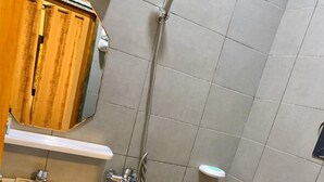 Uma casa de banho pequena com uma sanita branca, lavatório e zona de duche.