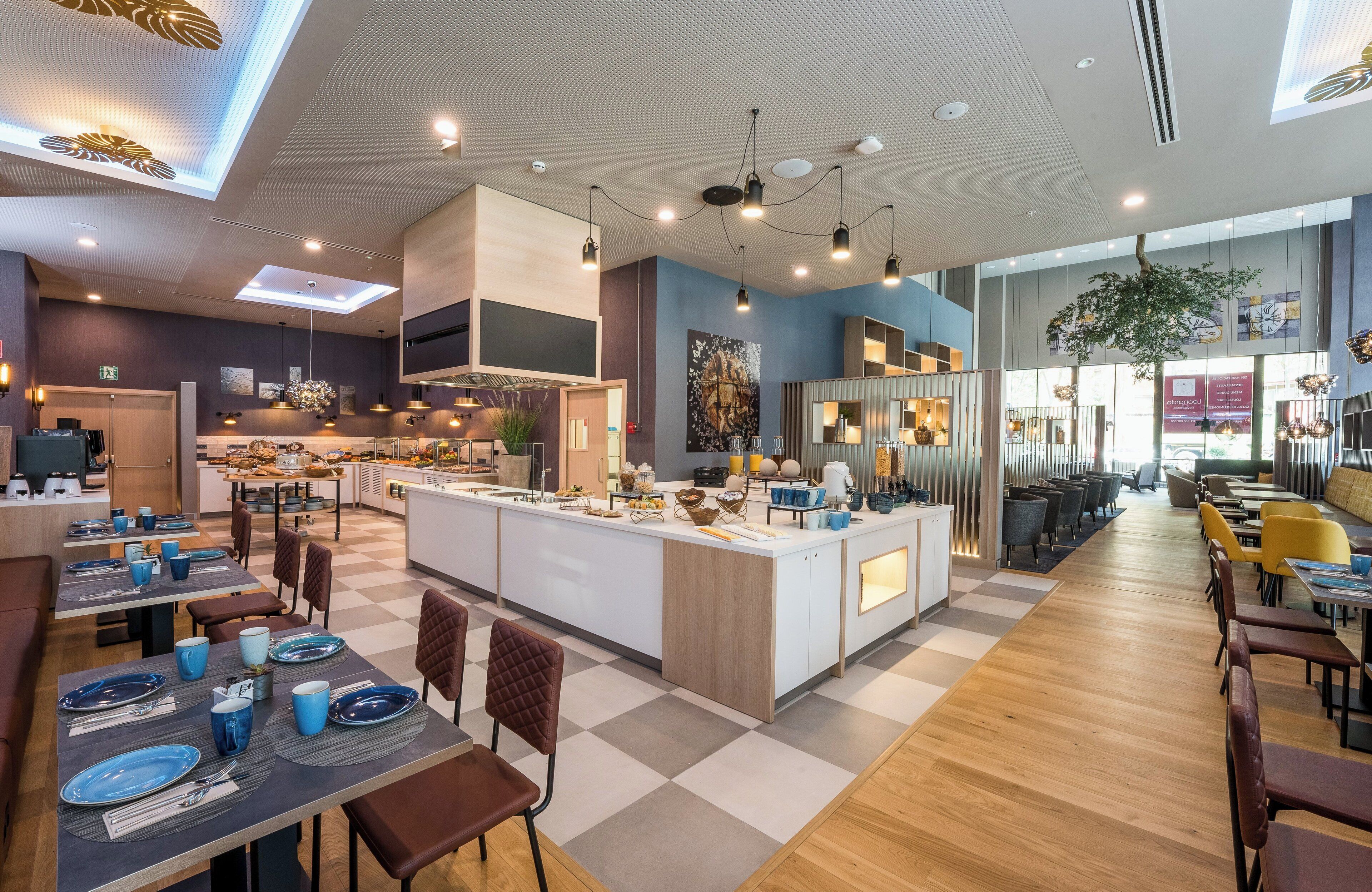 A modern restaurant with a central island, wooden flooring, and contemporary lighting fixtures.