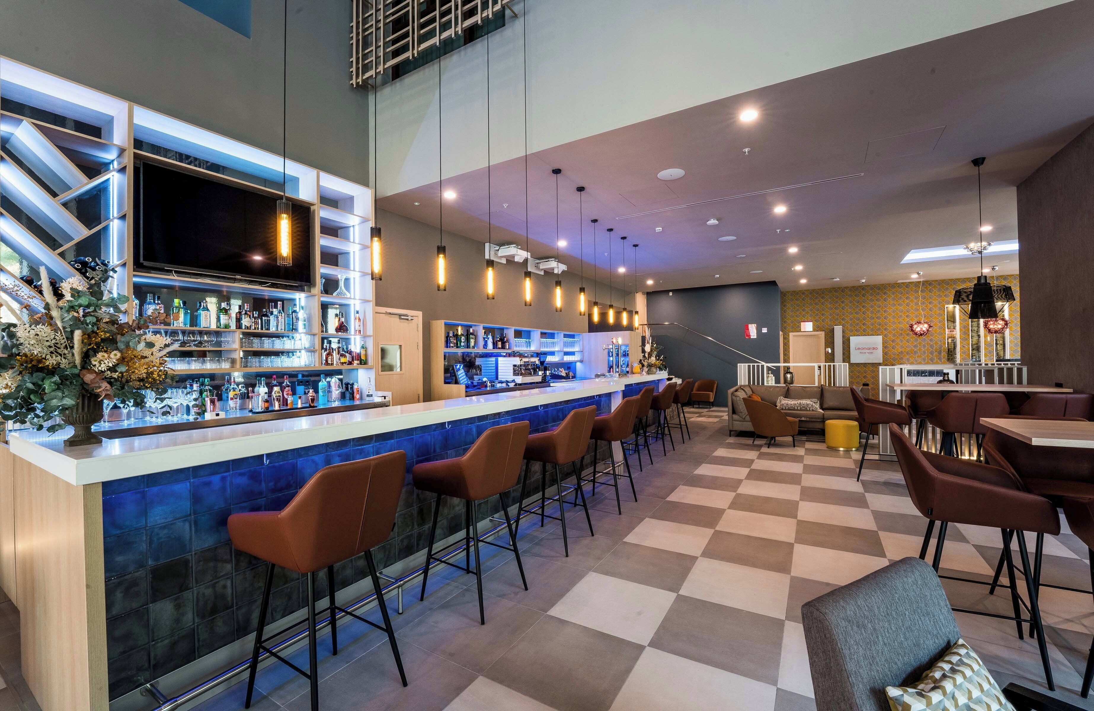 A bar area with a checkered floor, bar stools, and a counter with a TV.