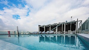 Ein moderner Poolbereich mit klarem, blauem Wasser, Liegestühlen und einer gläsernen Struktur.