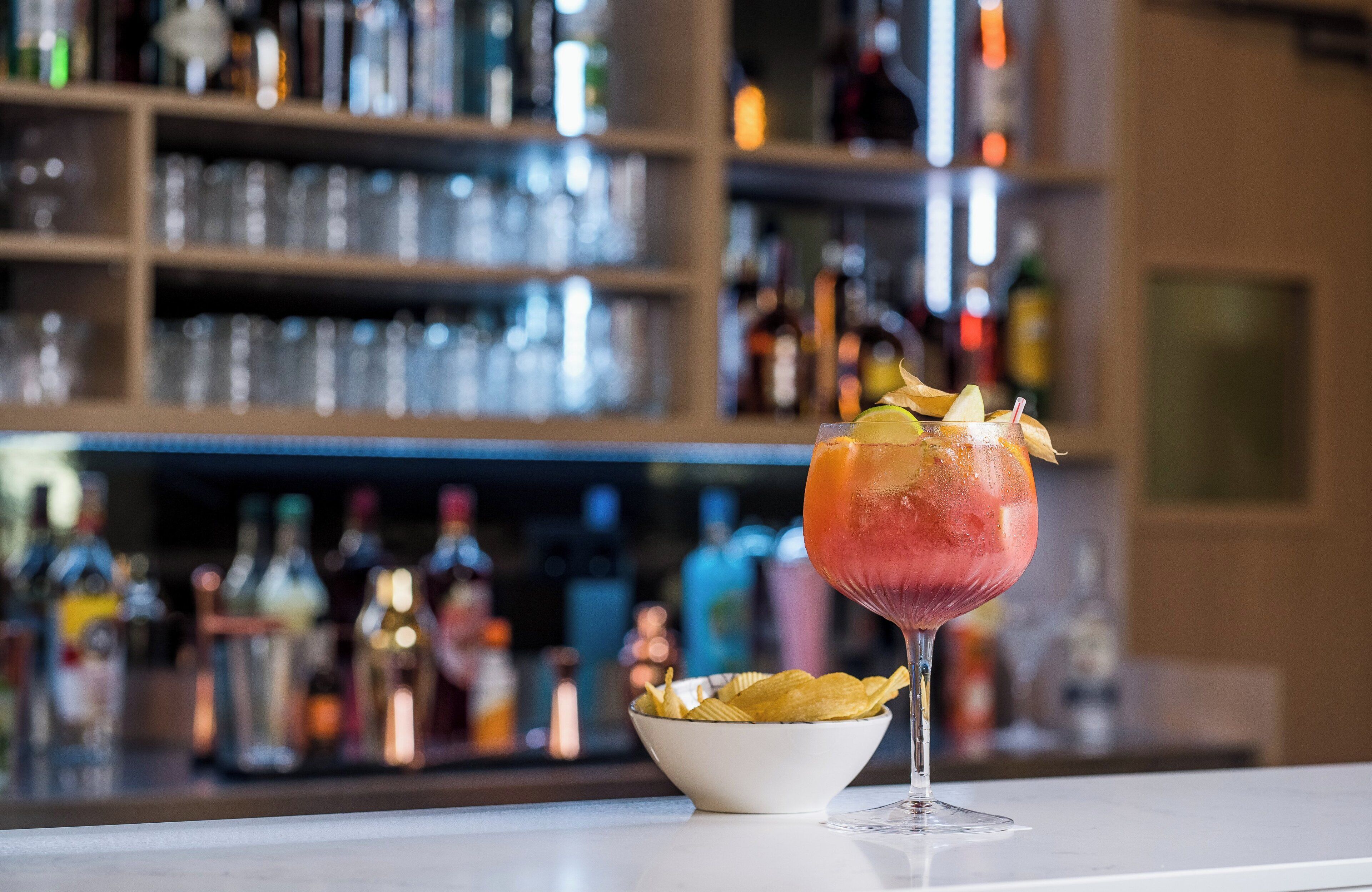 Un bar con un cóctel en un vaso y un tazón de papas fritas.