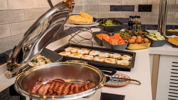 Un aparador de buffet amb diferents plats, incloent ous, bacon, verdures i amanides.