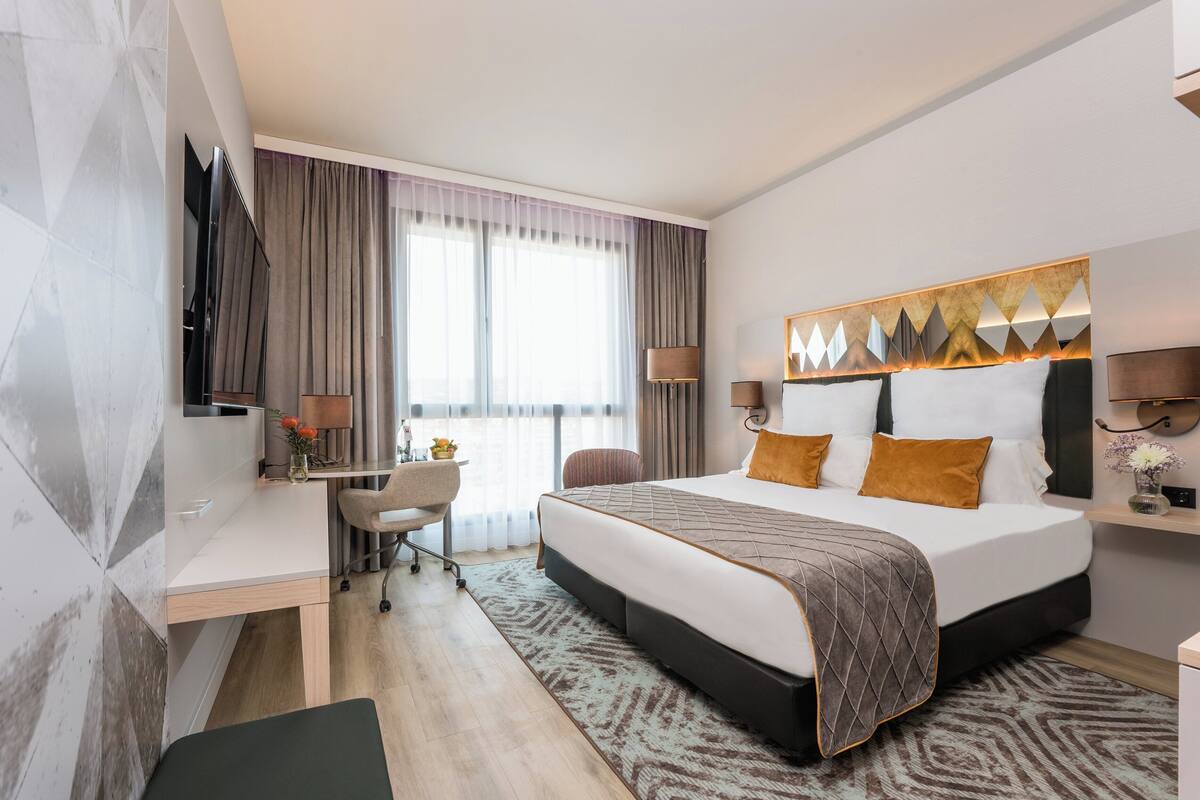 Une chambre d’hôtel moderne, dotée d’un grand lit, d’un bureau et d’une télévision.