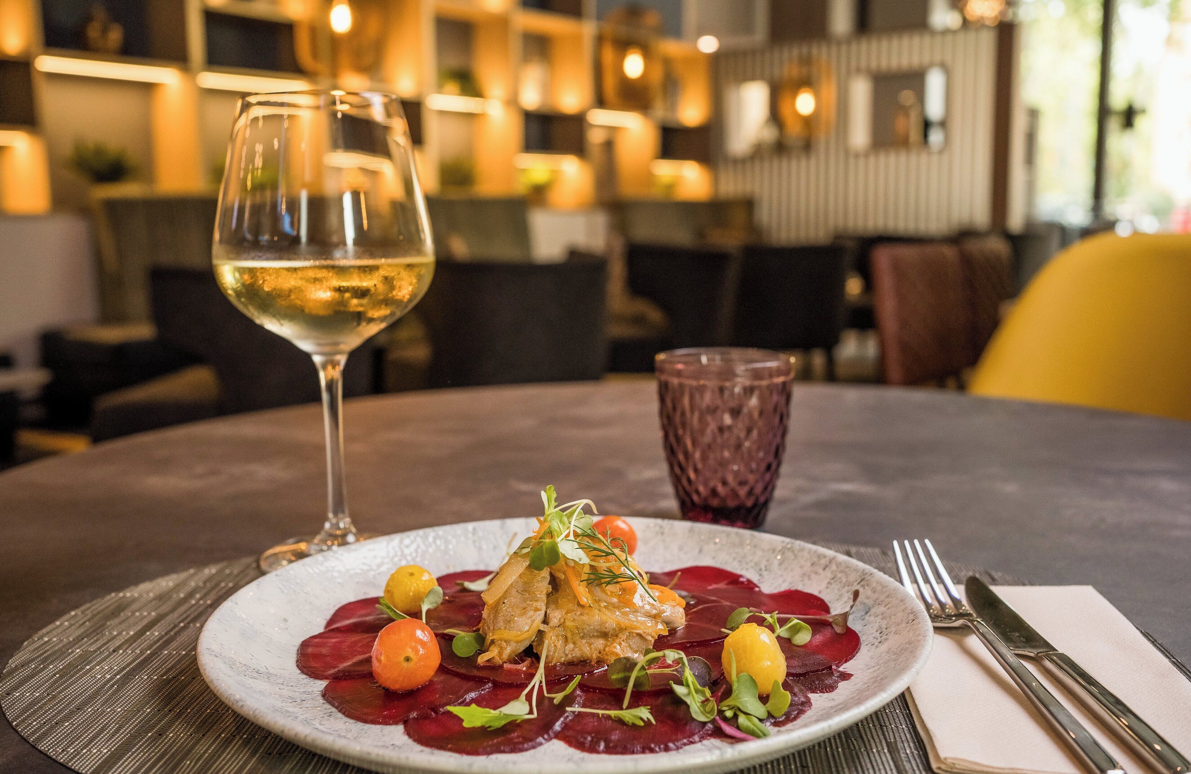 Ein Esstisch mit einem Teller Essen, einem Glas Weißwein und einem Glas Rotwein.