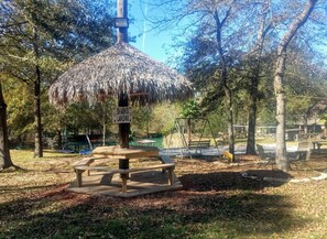 A park with a thatched gazebo, picnic tables, and a sign indicating 'Sharks Landing'. - West Wing at the Manor w/ Swimming Pond & Sand Volleyball Access (Montgomery)