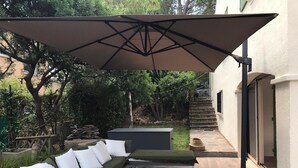 Um pátio com um sofá, uma mesa de jantar e um guarda-sol.