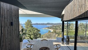 Un espace de restauration extérieur moderne offrant une vue sur la mer et les collines.