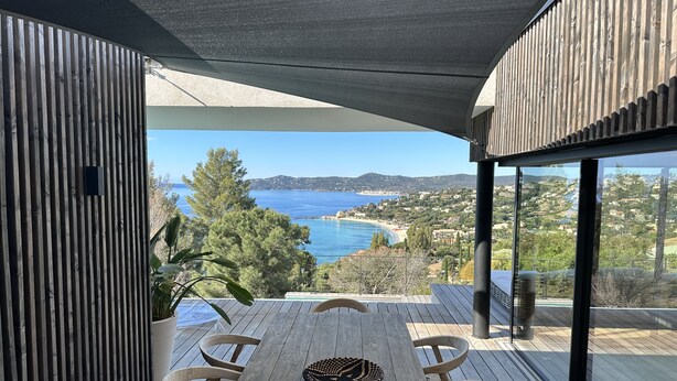 Un espace de restauration extérieur moderne offrant une vue sur la mer et les collines.