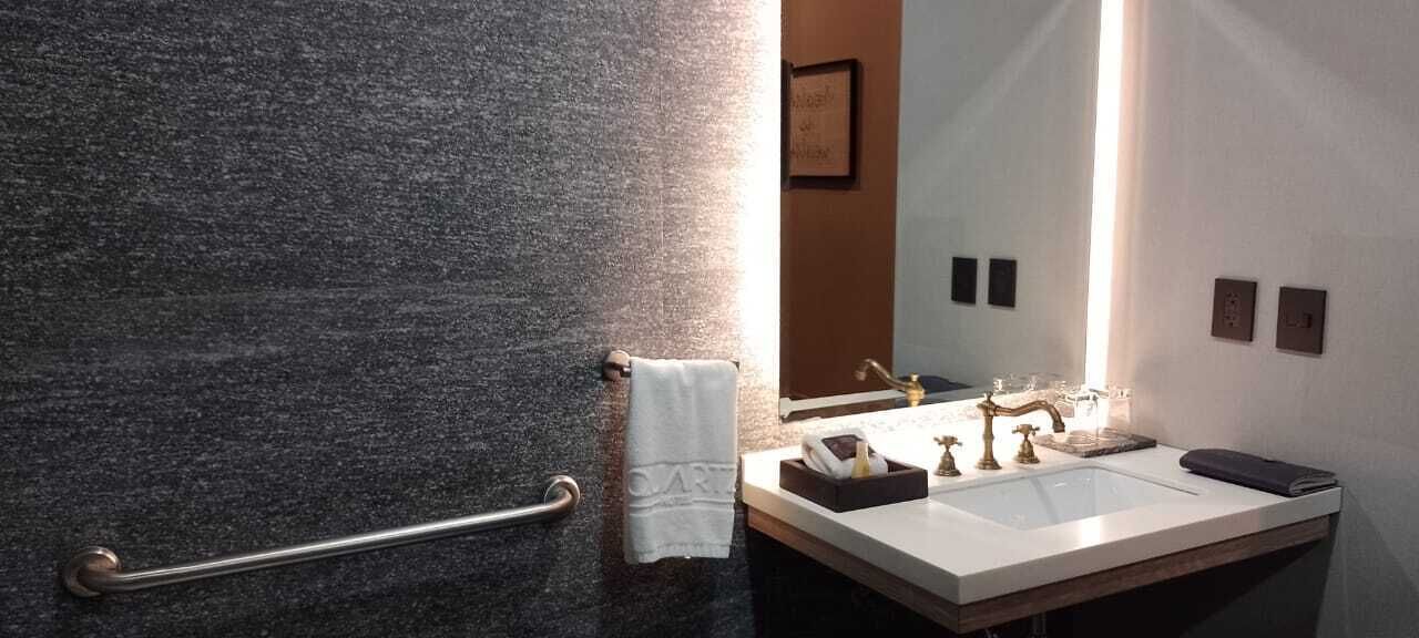 A bathroom with a granite countertop, a sink, a mirror, and a towel rack.