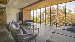 Un espacio habitable amplio con muebles modernos, ventanas grandes y vistas a árboles.