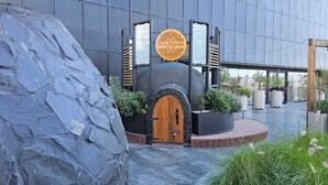 Un edificio moderno con fachada de piedra, puerta de madera y un letrero circular con texto.