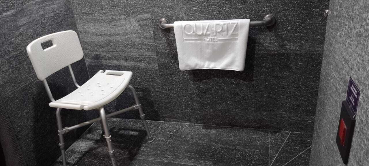 A bathroom with a white chair, a towel rack with a towel, and a granite wall.