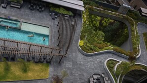 Vista aérea de un moderno resort con piscina, áreas de descanso y jardines ajardinados.