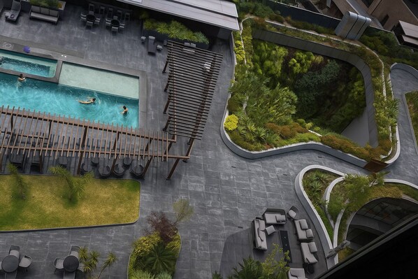 An aerial view of a modern resort with a swimming pool, lounge areas, and landscaped gardens.