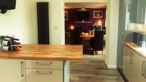 A modern kitchen with wooden countertops, a built-in oven, and a dining area with a table and chairs. - Yorkshire Wolds Spacious Modern Holiday Bungalow (Driffield)