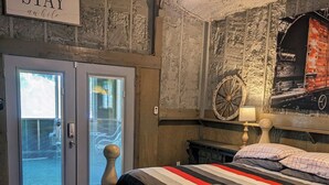 Una camera da letto con un letto, un cartello con la scritta “STAY awhile” e una grande ruota appesa al muro.