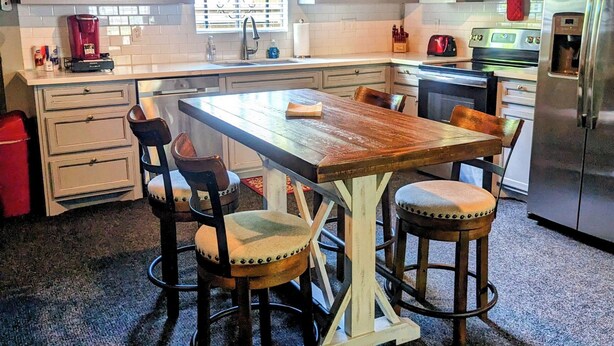 Una cucina con isola centrale, sgabelli da bar, frigorifero e forno a microonde.