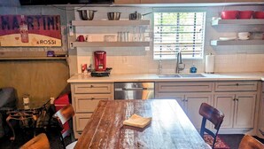 Una cucina con un tavolo di legno, sedie, una televisione e una finestra con persiane.