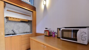 A kitchen with wooden cabinets, a built-in microwave, a kettle, and a coffee maker. - IzzHome Full Center Grand (Cagliari)