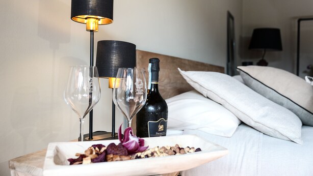 Et pænt anrettet bord med en vinflaske, to glas og en tallerken mad på et hotelværelse.