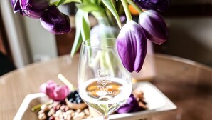 Et glas med et logo og en buket lilla tulipaner på et træbord.