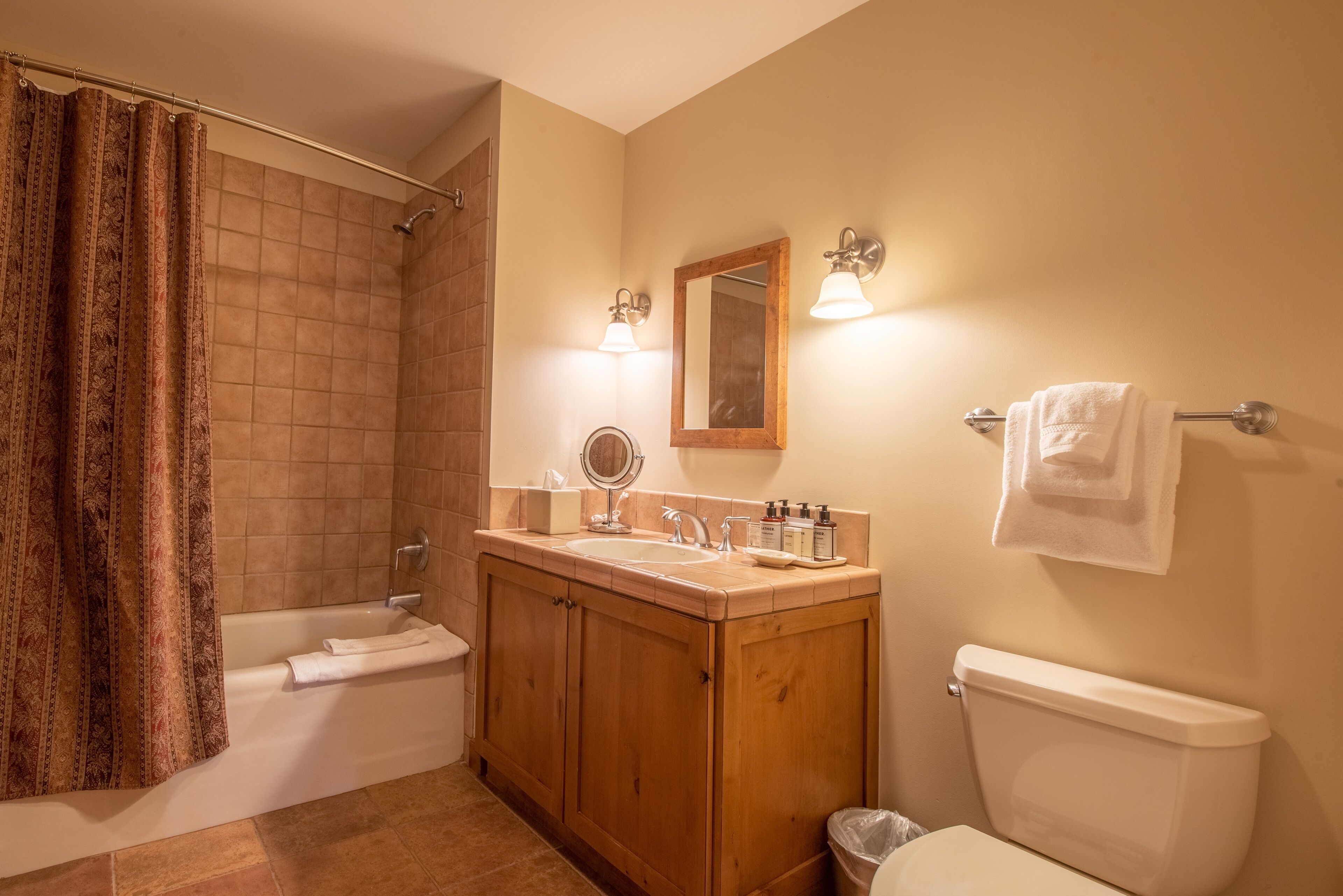 A bathroom with a shower, a bathtub, a toilet, wooden cabinets, a sink, and a mirror.