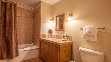 A bathroom with a shower, a bathtub, a toilet, wooden cabinets, a sink, and a mirror.
