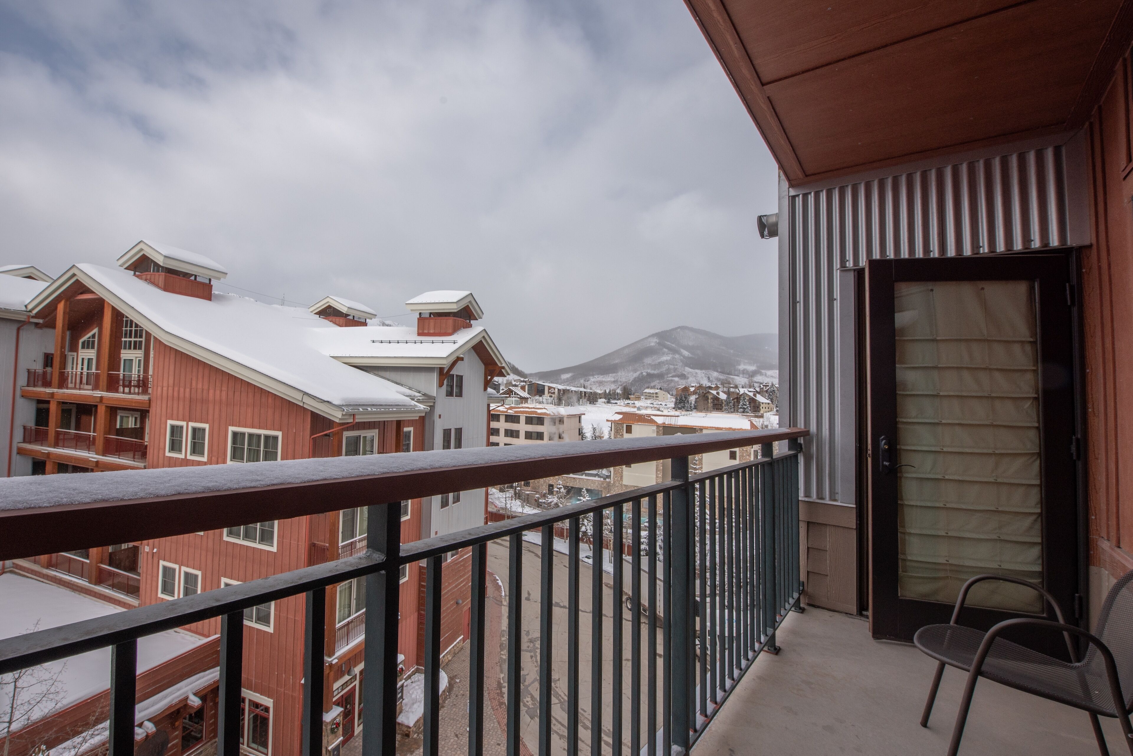 A balcony with a view of a snow-covered mountain and buildings.