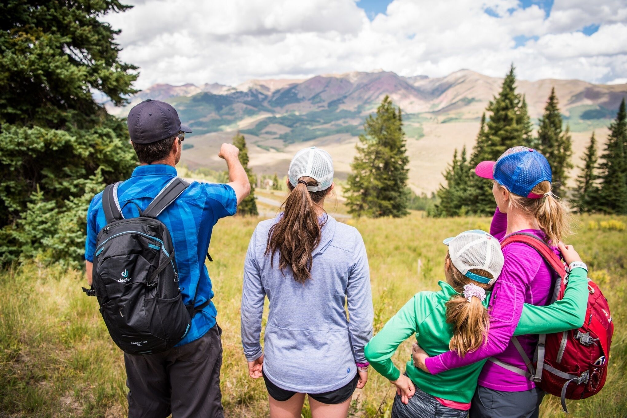 A group of people hiking on a trail with a mountainous landscape in the background.