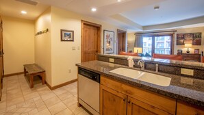 A kitchen with granite countertops, wooden cabinets, a dishwasher, and a large window. - Comfortable 1 Bedroom Slopeside Condo - No Cleaning Fee! by RedAwning (Crested Butte)