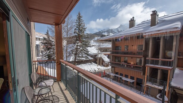 Un balcon donnant sur une montagne enneigée et des bâtiments.
