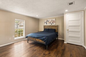 Une chambre à coucher avec un lit, une fenêtre, une porte et une grille d’aération au plafond.
