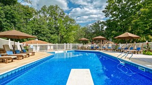 A swimming pool with lounge chairs and umbrellas, surrounded by a white fence and trees. - Endless Family Fun @ Private LUX Retreat Sleeps 25 (Annville)