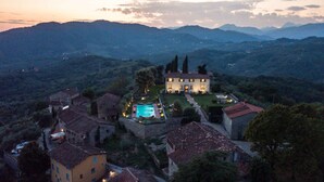 Una villa con piscina, circondata da case a schiera, con montagne sullo sfondo.