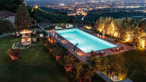 Una piscina rettangolare con vista su una città al crepuscolo.