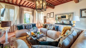 Un accogliente soggiorno con soffitto in legno, un lampadario centrale e un divano.