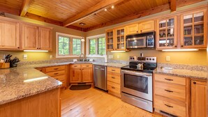 A kitchen with wooden cabinets, granite countertops, stainless steel appliances, and a wooden ceiling. - Cozy Dog Friendly Blue Home Near Lake w/ Huge Yard (Swanton)
