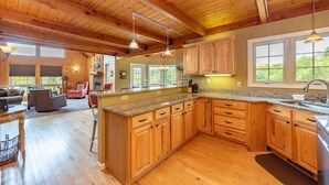A spacious kitchen with wooden cabinets, granite countertops, and a large island. - Cozy Dog Friendly Blue Home Near Lake w/ Huge Yard (Swanton)