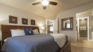 A bedroom with a bed, a ceiling fan, and a bathroom visible through an open door. - Spectacular Condo In Downtown Whitefish, Close To Glacier Park, Skiing And Golf (Whitefish)
